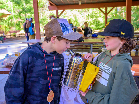 campers checking out a smoke canister for taming bees
