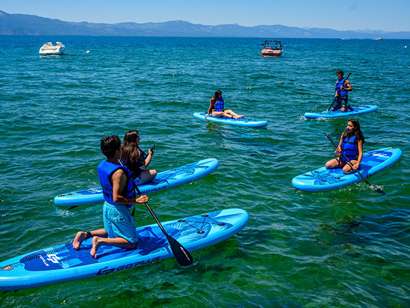 campers playing on stand up paddle boards