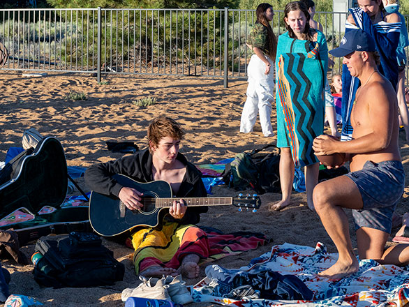 camper playing guitar on the beach