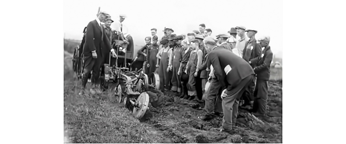 Group of people looking at an old piece of farm equipment.