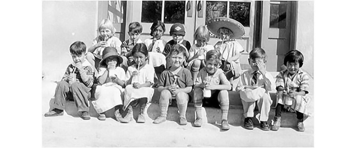 Group of children sitting in front of building.